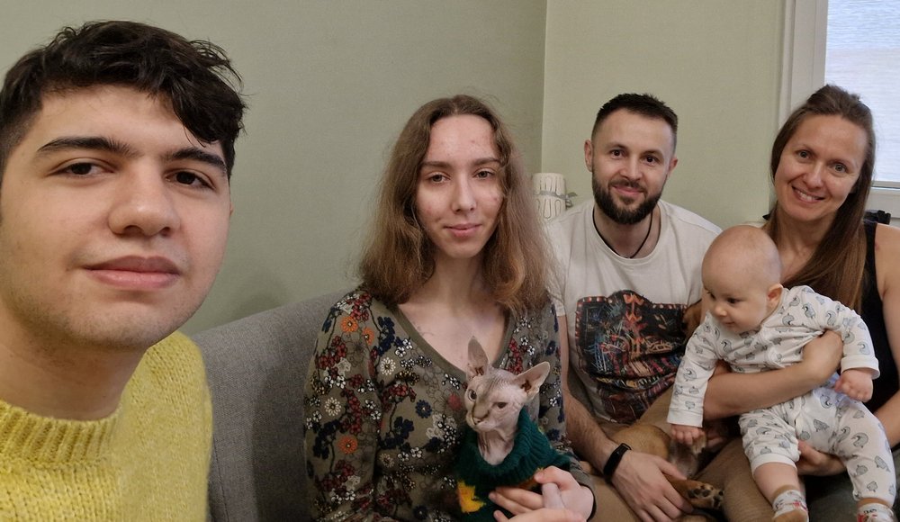 Participants of the University of Lodz "Christmas Guest" campaign, two men and two women smiling at a child, one of the women is holding a baby