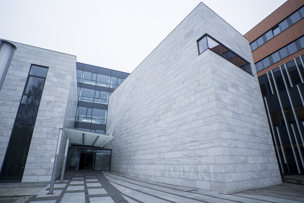 Budynek Wydziału Filologicznego Uniwersytetu Łódzkiego. Ściana z szarych dużych bloków granitu z szklanymi drzwiami.