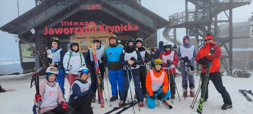 Zdjęcie grupowe uczestników obozu narciarskiego na tle kolejki górksiej z napisem "Jaworzyna-Krynicka 1114 m n.p.m."