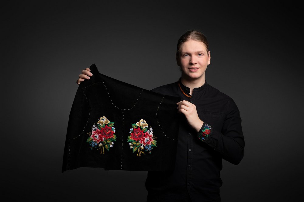Piotr Pejski trzyma prezentuje strój ludowy 