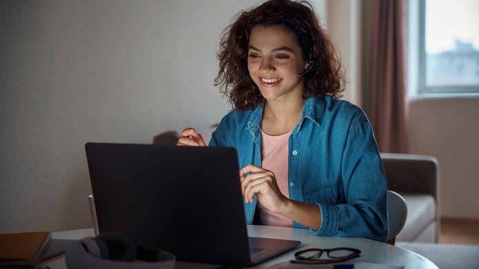 A student is smiling in front of her laptop.