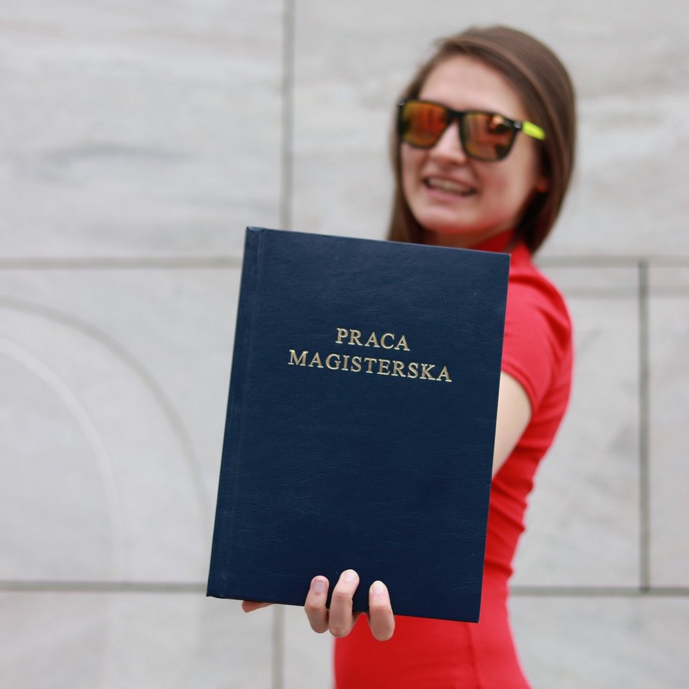 studentka trzymająca pracę magisterską