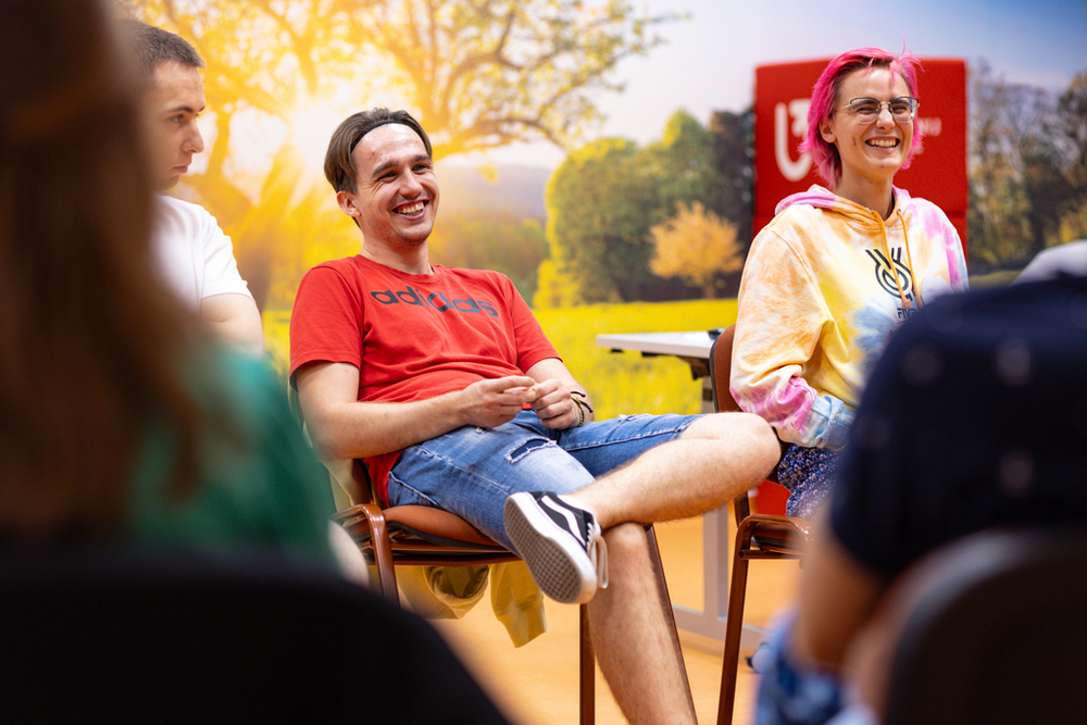 student i studentka siedzą na krzesłach i uśmiechają się